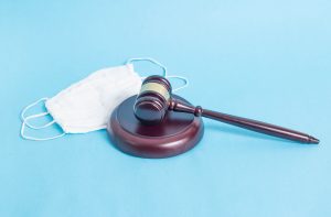 Judicial gavel and protective medical mask on a blue background. Concept of illegal resale of protection masks and over-resale during the coronavirus pandemic